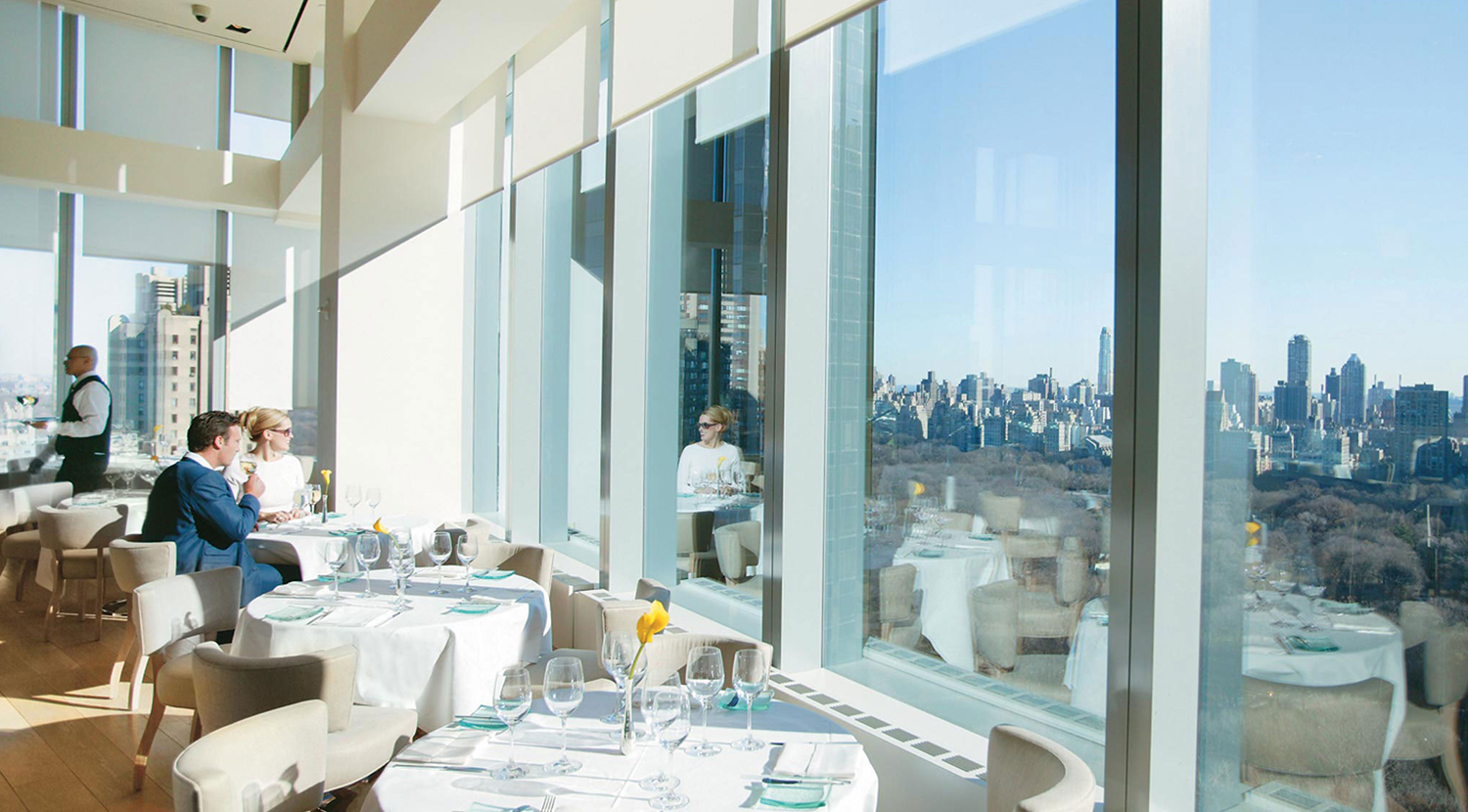 Manhattan high-rise restaurant, with large windows covered by cream white, motorized Lutron Contract Rollers