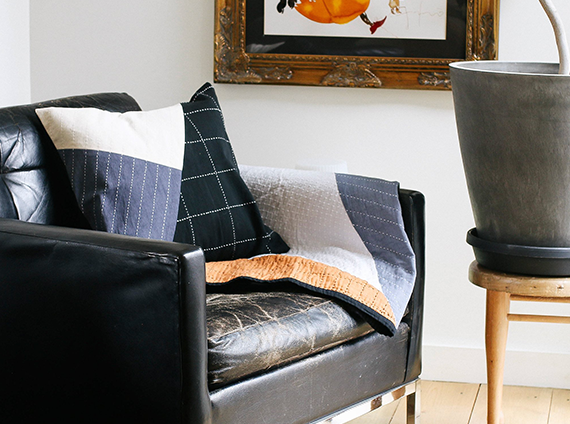 Worn black leather chair with an Anchal quilt throw and pillow in various colors