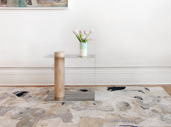 Hand knotted rug, in a variety of light pastel colors and black with a side table on top