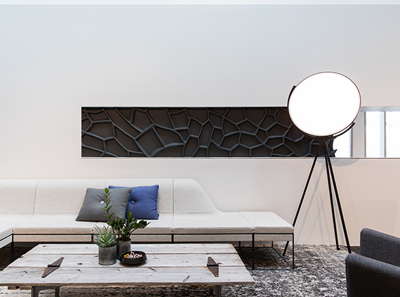 Superloon circular lamp, on black tripod posts, in a light toned room next to a white sofa