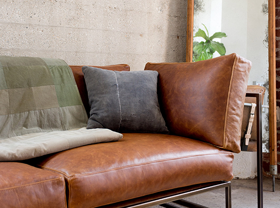Stephen Kenn steel framed brown leather sofa, with a pillows and a quilt