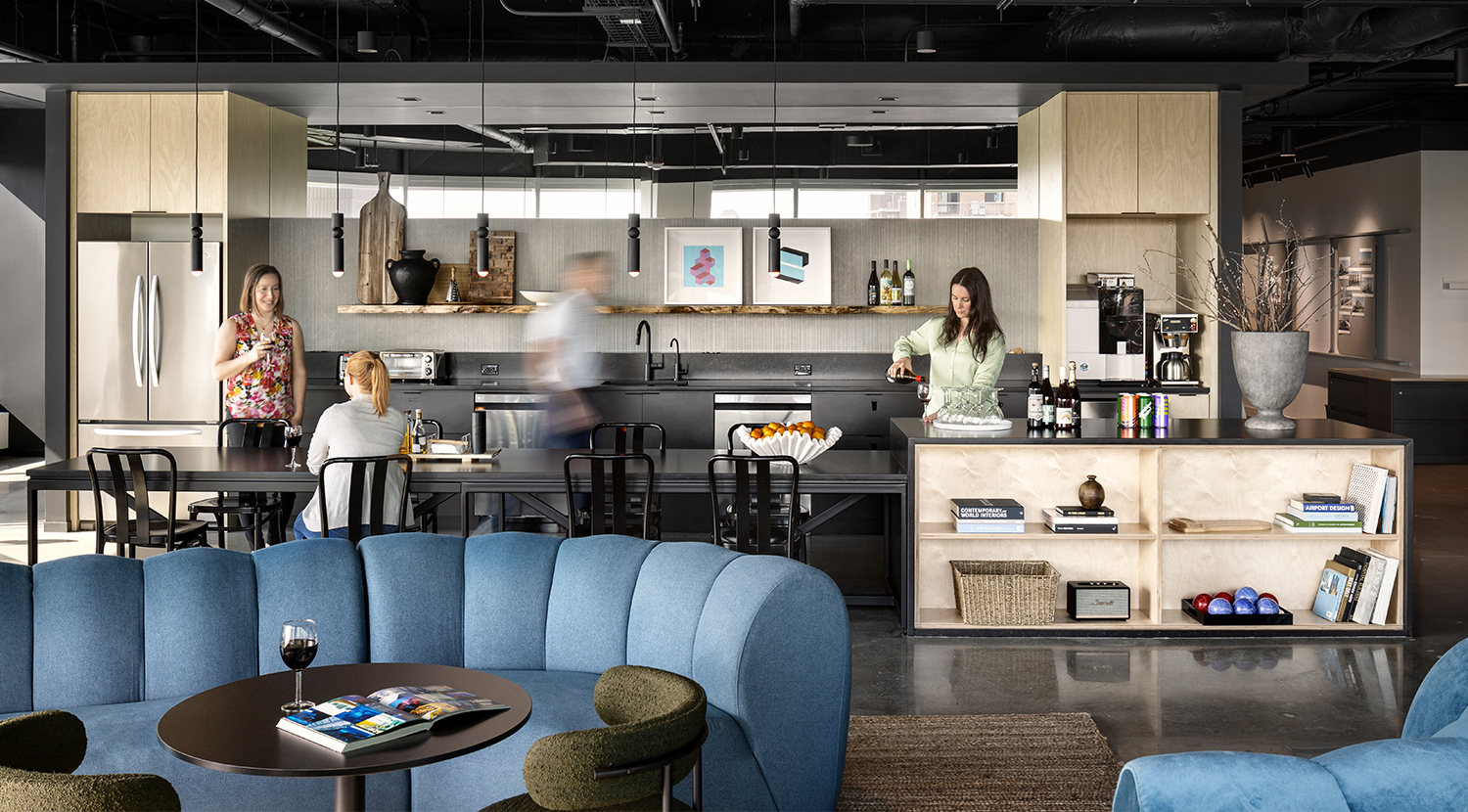 Busy work cafe with blue tufted sofa, round charcoal table and side chairs