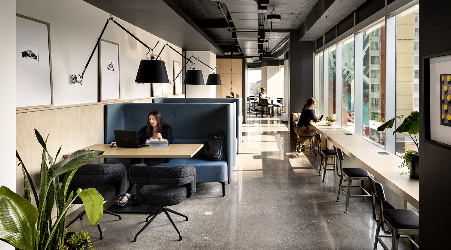 Counter with metal chairs facing windows, blue high back seating and charcoal side chairs across tables along wall