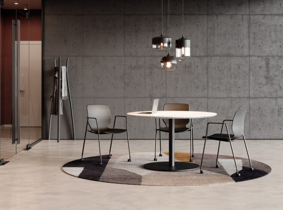 Three black chairs with casters in a meeting room around a round table with an open laptop