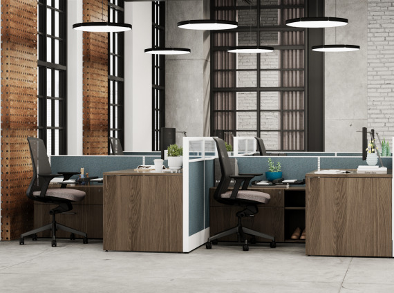 A image of 4 work stations, dark brown wood tone desks; black chairs and blue/white cubicle walls